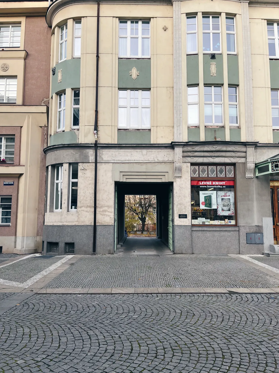 Ulice s obchodem Levné knihy, žlutozelená fasáda a klenutý průchod do dvora