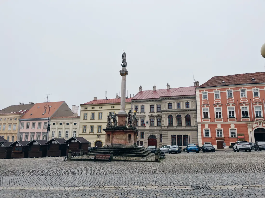 Mariánský morový sloup na Velkém náměstí v Hradci Králové s barevnými domy v pozadí