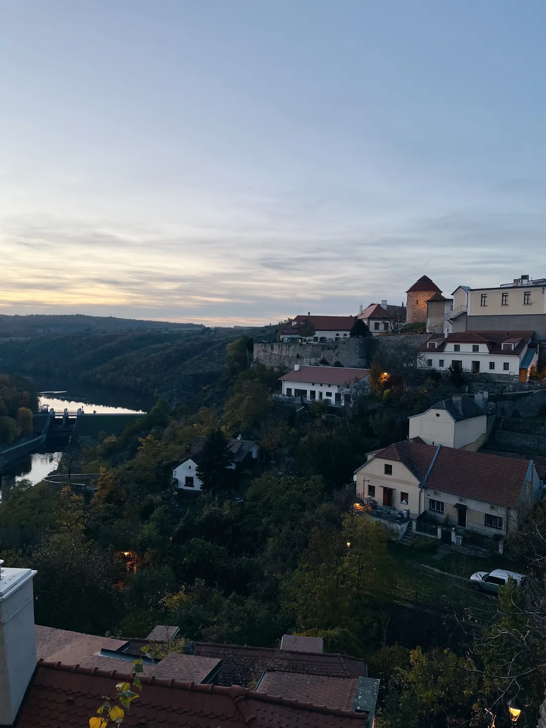 Večerní pohled na Znojmo s červenými střechami, hradební zdí a přehradou na řece Dyji v údolí