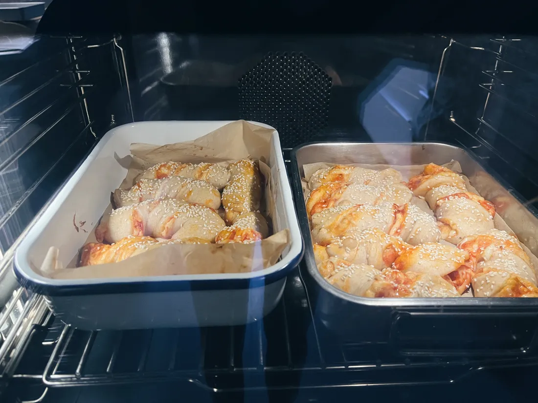 V troubě dva plechy s upečenými pizzeriovými špirálami posypanými sezamem na pečicím papíru