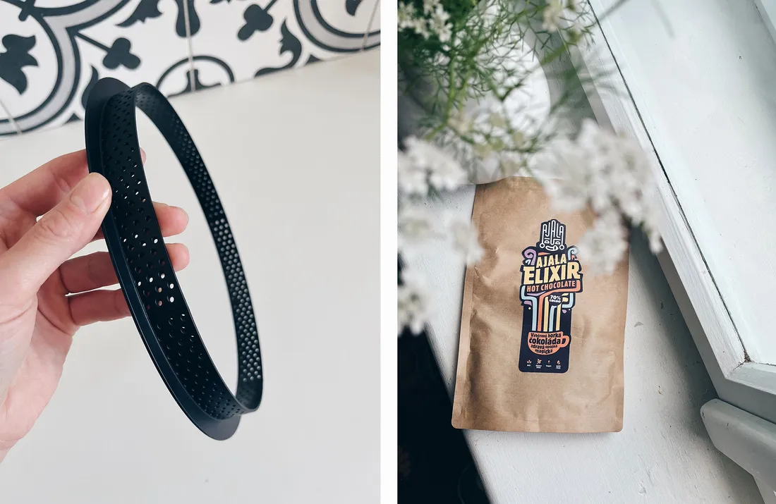 Černý děrovaný ráfek na pečení v ruce a sáček horké čokolády Ajala Elixir na parapetu