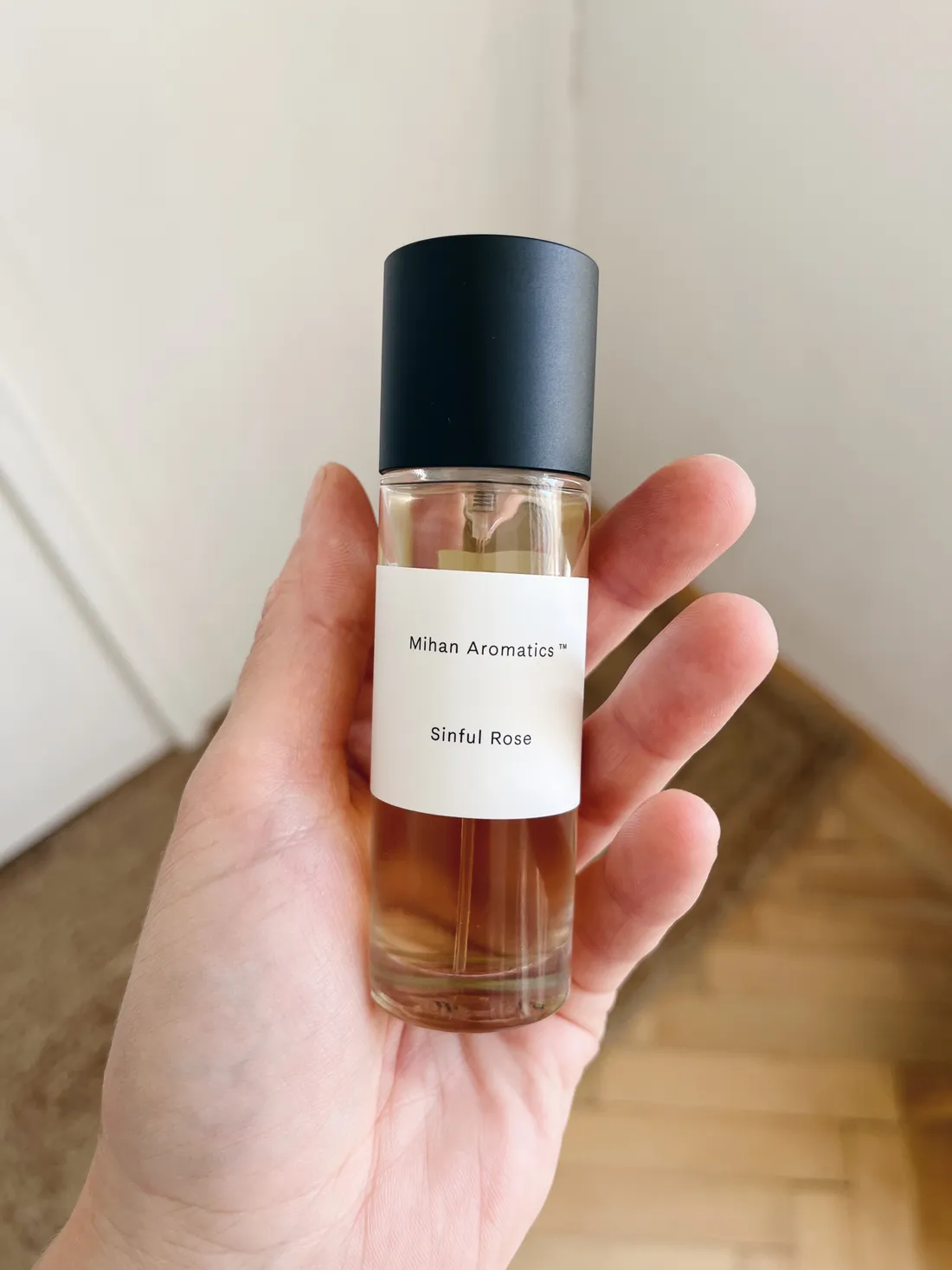 Ruka drží flakonek parfému Sinful Rose značky Mihan Aromatics