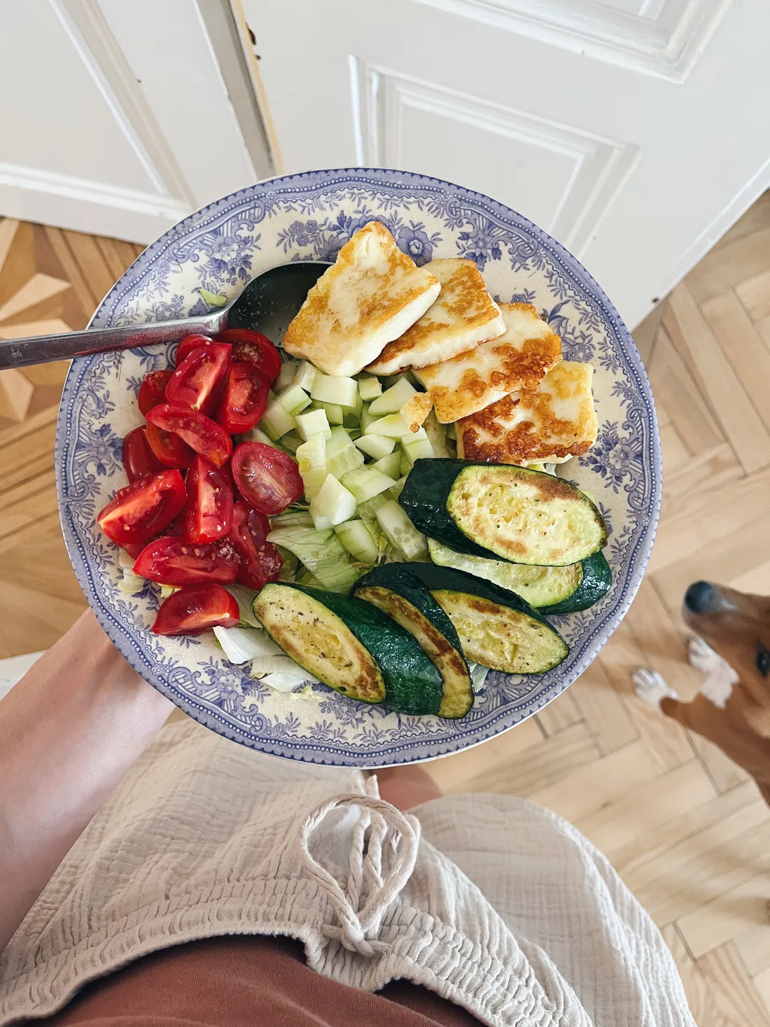 Miska zeleninového salátu s halloumi, pečenou cuketou a rajčaty na talíři