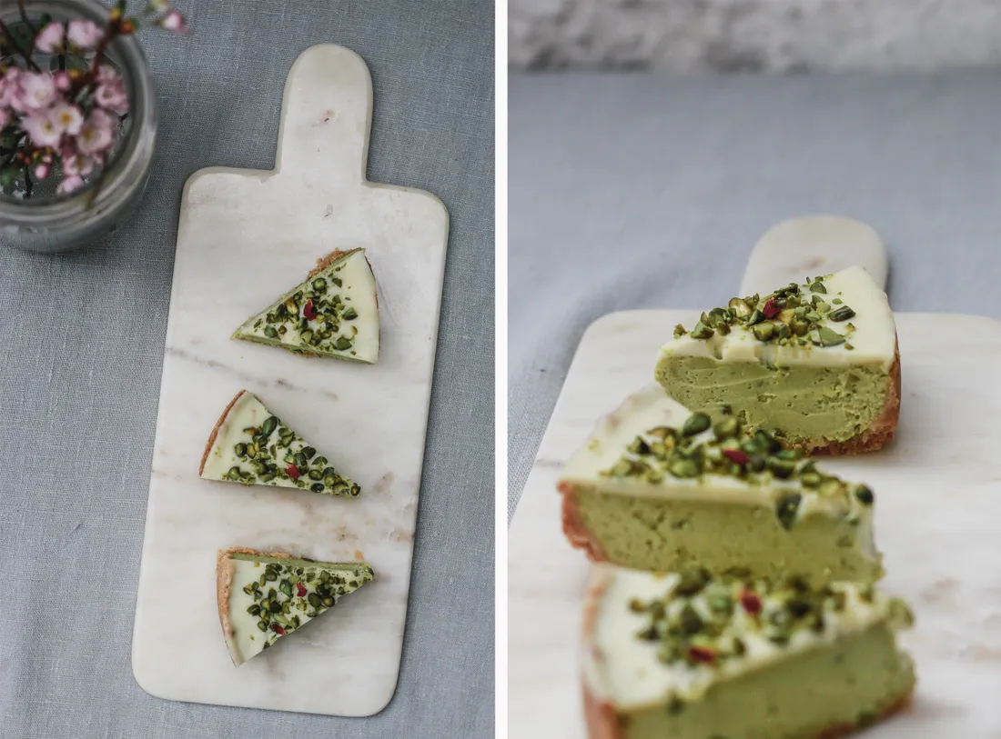 Pistáciový cheesecake se světle zeleným krémem a polevou z bílé čokolády, řezy na mramorovém podkladu