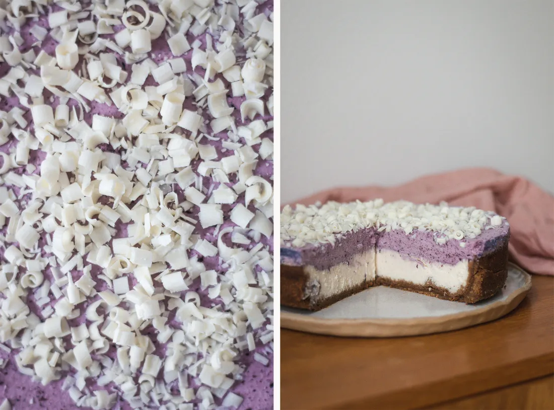 Vanilkový cheesecake s borůvkovou pěnou a hoblinkami bílé čokolády na dřevěném stole, celý dort a řez