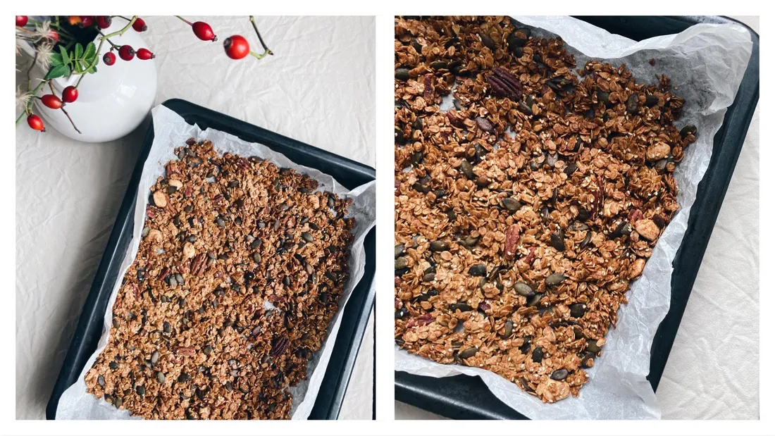 Zlatá křupavá granola s ořechy, vločkami a dýňovými semínky na plechu s papírem, v pozadí váza se šípky.
