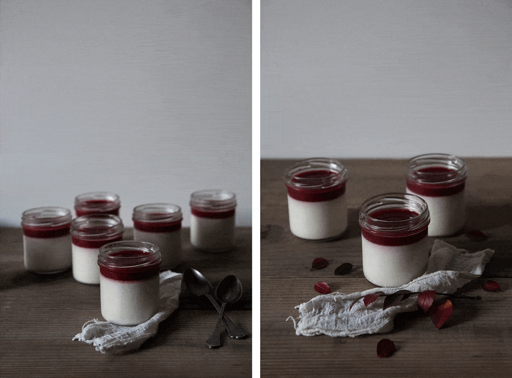 Bílá kokosová panna cotta v malých skleničkách s červeným malinovým pyré na tmavém dřevěném stole.