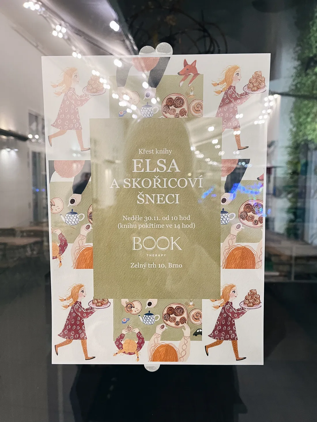 Plakát křtu knihy Elsa a skořicoví šneci na skle výlohy Book Therapy v Brně, ilustrace šneků a čaje.