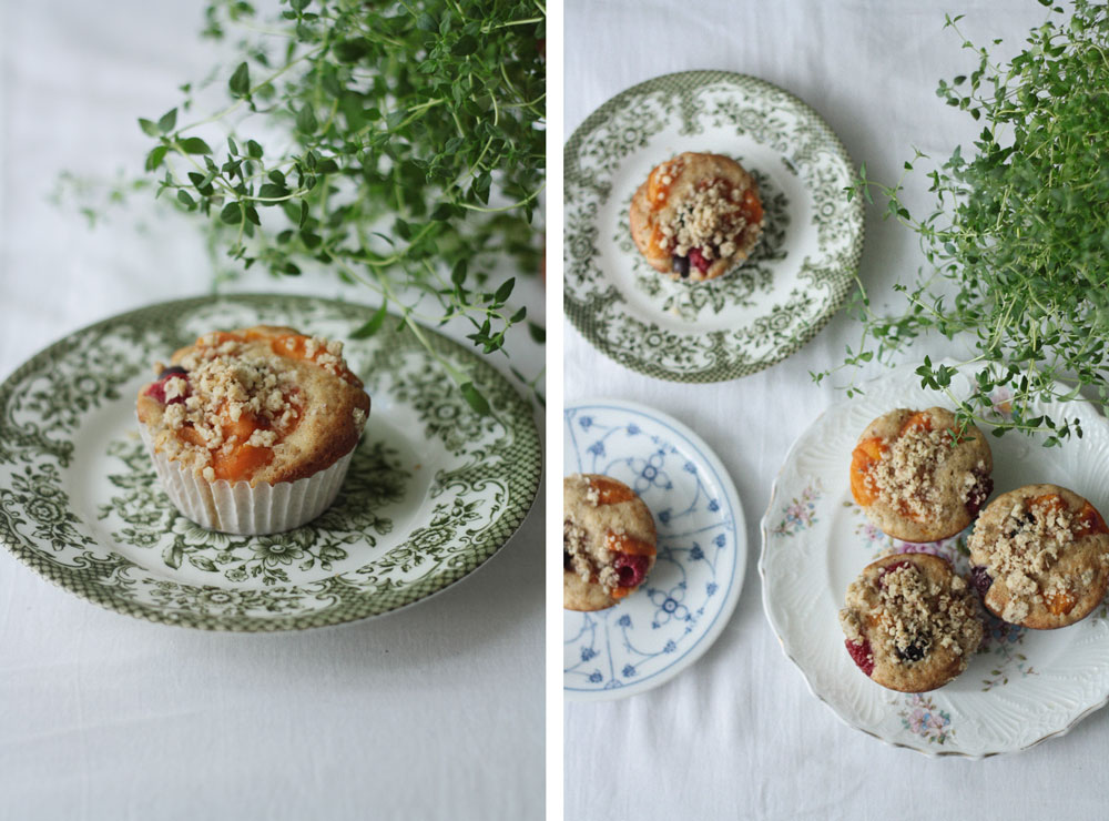 Ovocné muffiny s drobenkou na vintage talířích s květinovým vzorem a čerstvým tymiánem shora.