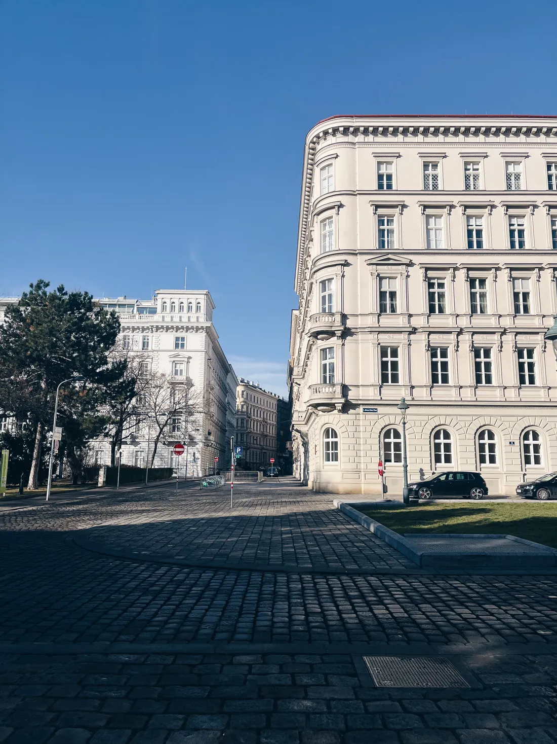 Historické budovy a dlážděná ulice ve Vídni pod modrou oblohou a sluncem.