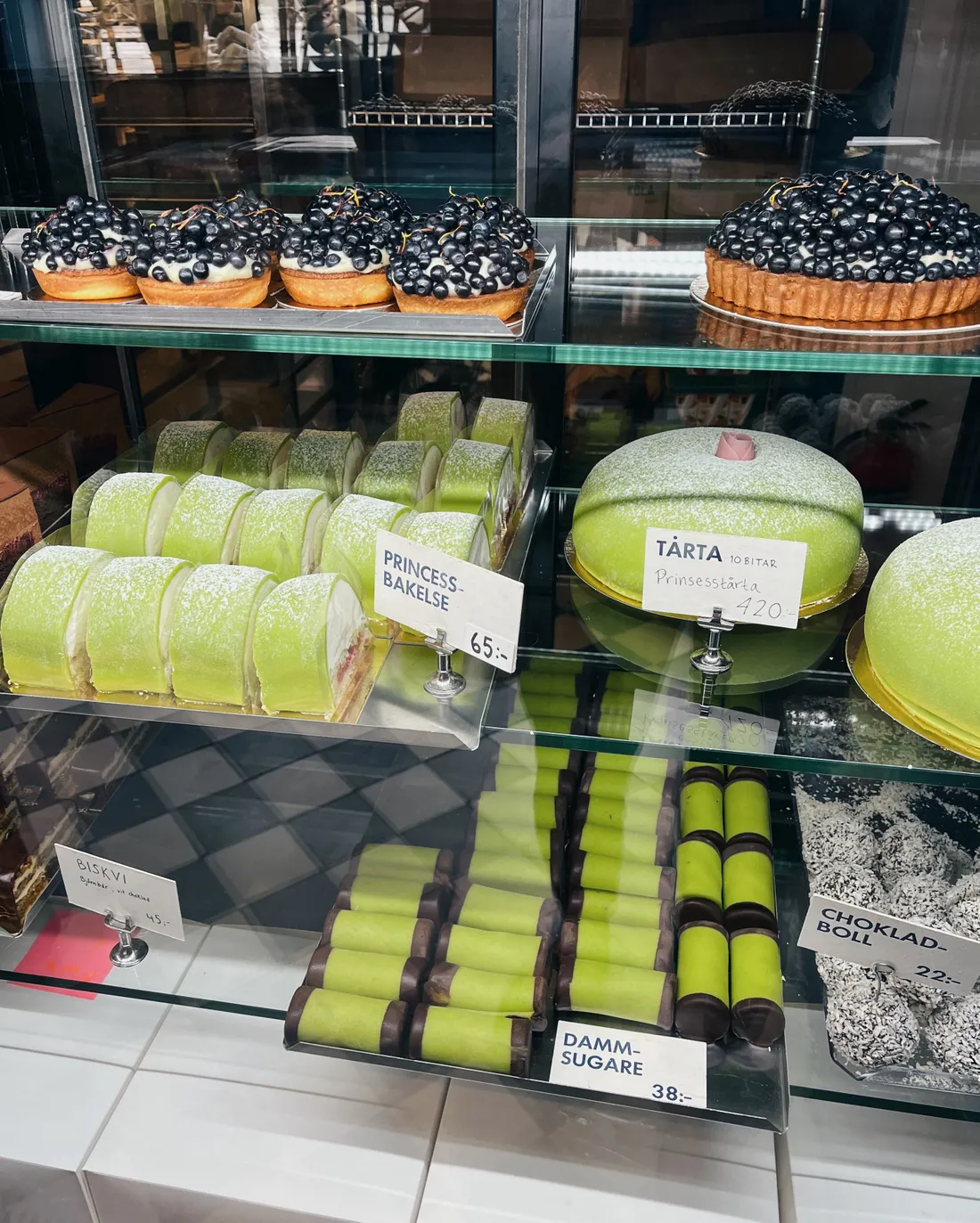 Vitrína švédské pekárny s princeznovými dorty, dammsugare, chokladboll a borůvkovými tartaletkami.