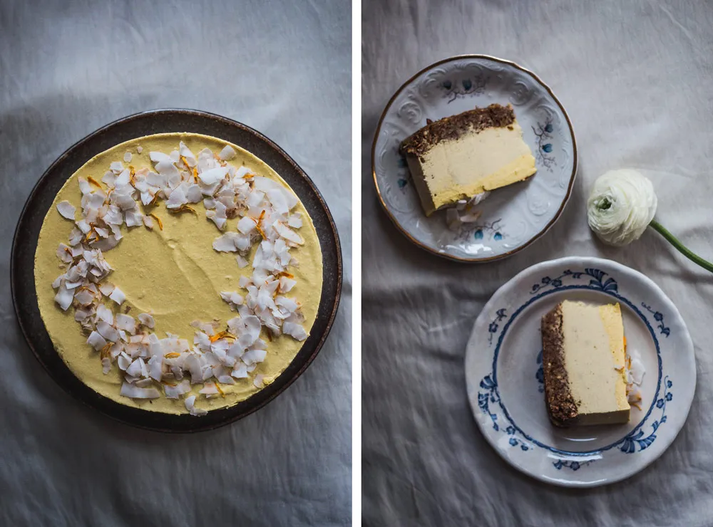 Raw mangový cheesecake s kokosem nahoře a nakrájené kousky s ořechovým korpusem na modrobílých talířích.