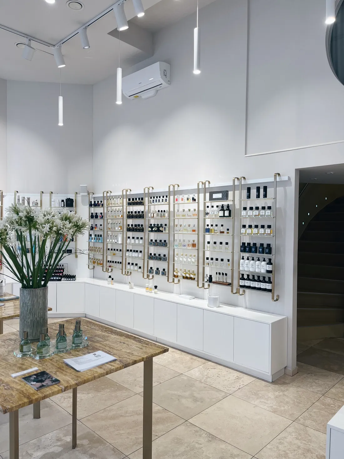 Interiér parfumerie s mosaznými regály plnými flakonů a kyticí kalůvků