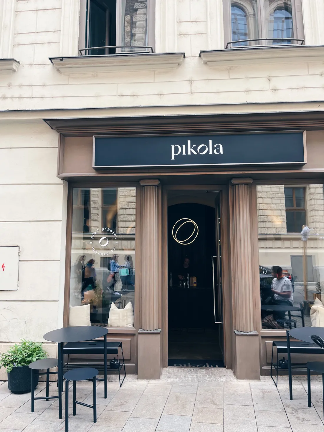 Exteriér kavárny Pikola s černým nápisem a venkovním posezením