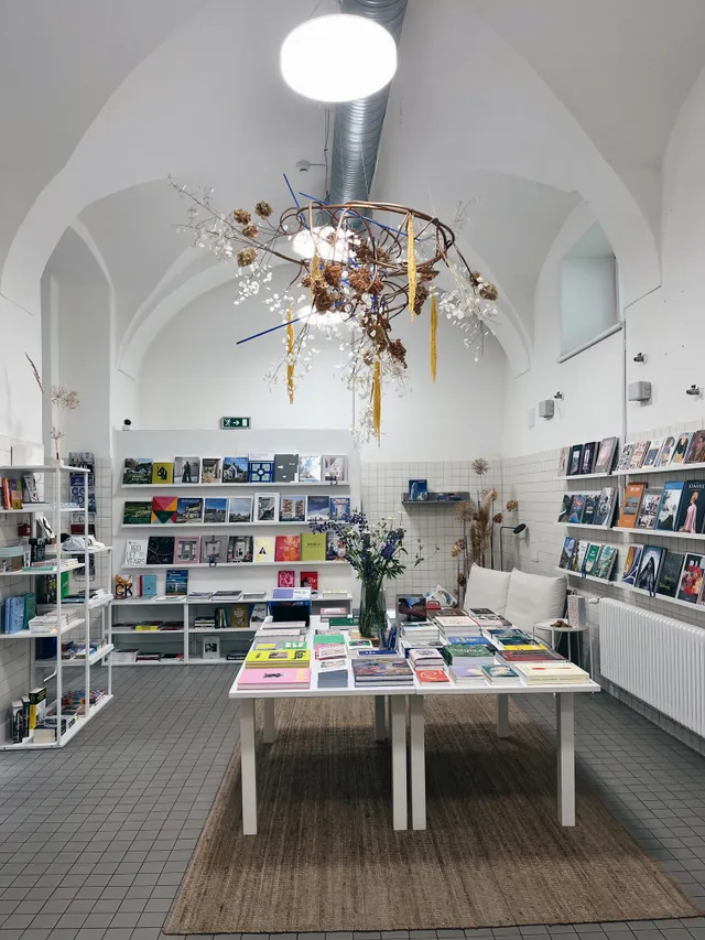 Interiér Book Therapy s knihami, květinovou instalací a klenutým stropem