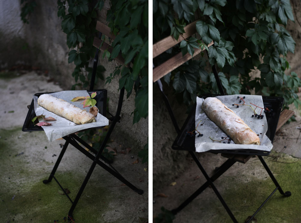 Hruškový závin posypaný cukrem na plechu na skládací židli v zahradě s podzimním listím a bobulemi.