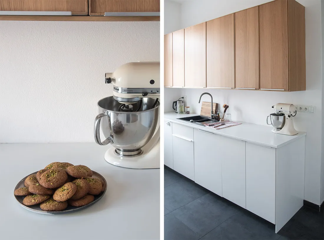 Talíř pistáciových sušenek u krémového kuchyňského robotu KitchenAid a celá bílá kuchyně.