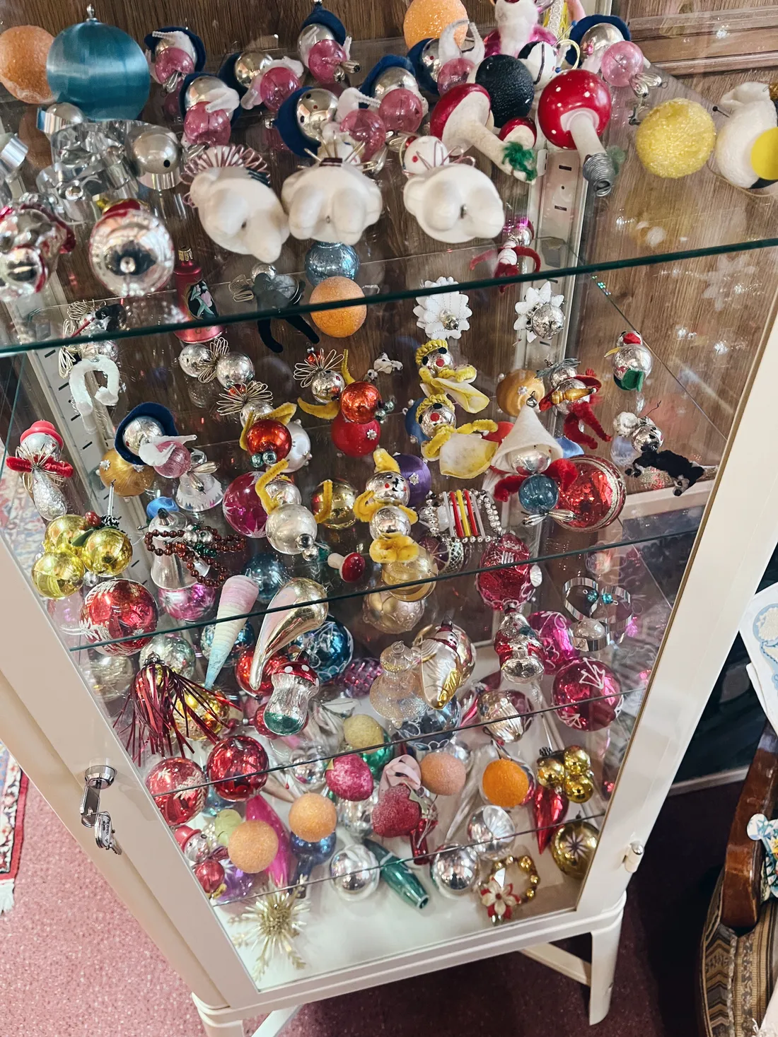 Skleněná vitrína plná retro vánočních ozdob, baňek, andělů a figur zvířátek.