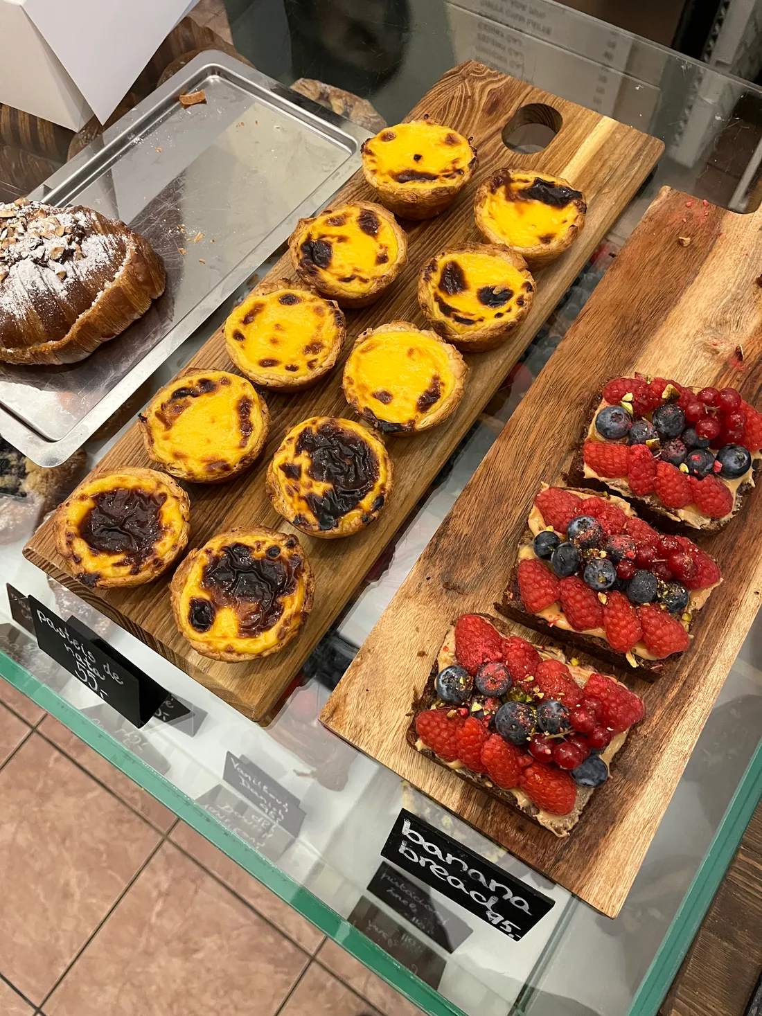 Výloha s pasteis de nata, banánovým chlebem s ovocem a mandlovým croissantem.
