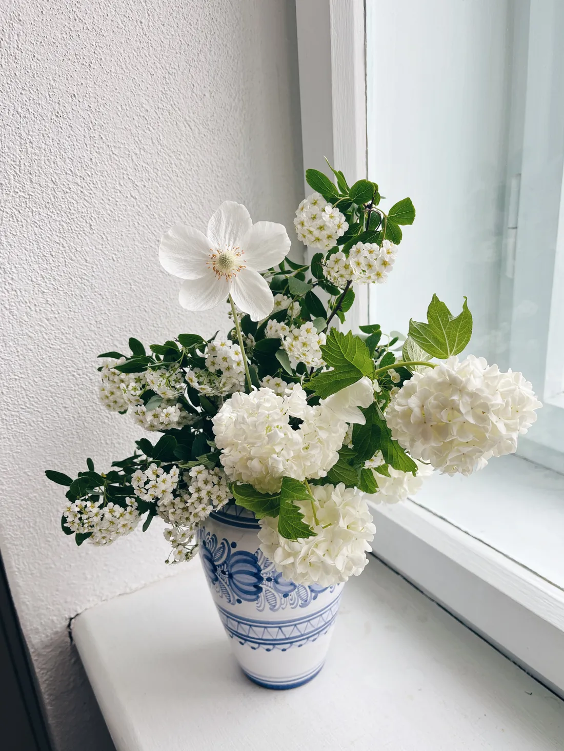 Bílá kytice v modrobílé váze na parapetu, šeřík a viburnum.