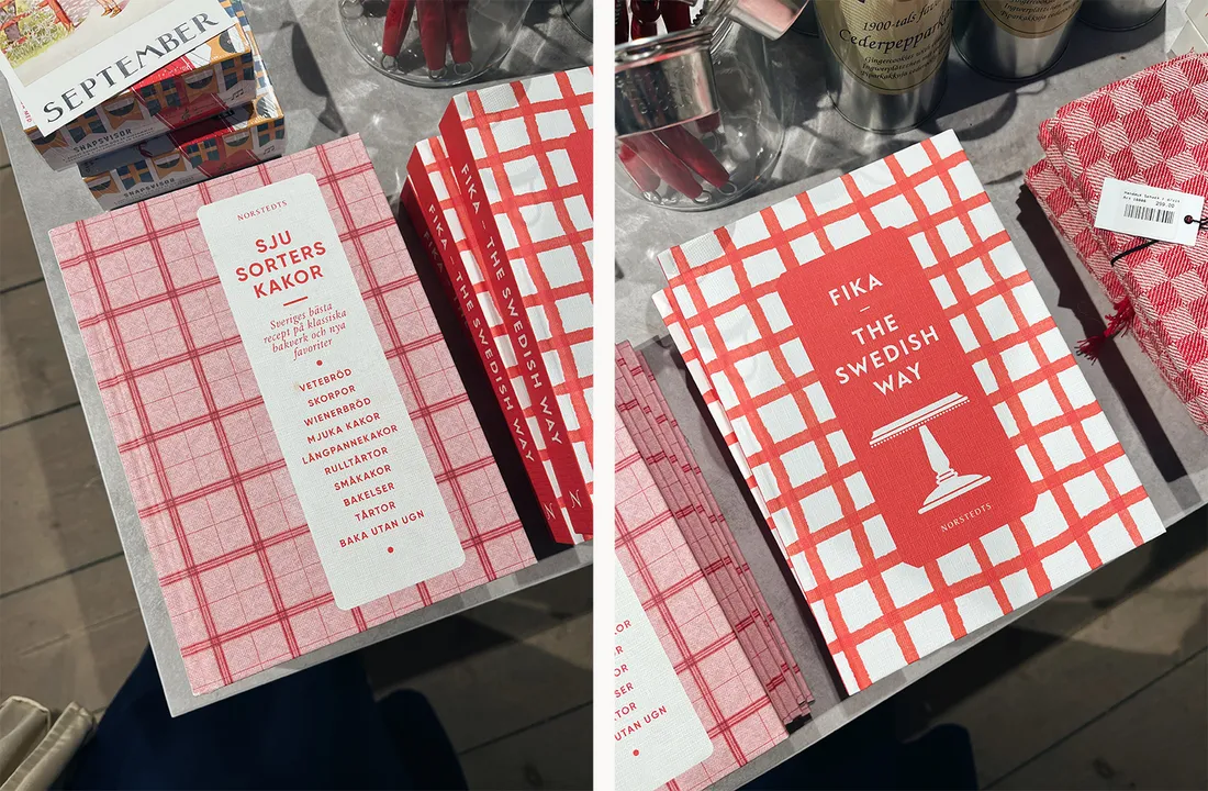Dvě švédské kuchařky Sju sorters kakor a Fika – The Swedish Way s červenobílým kostkovaným obalem na stole.